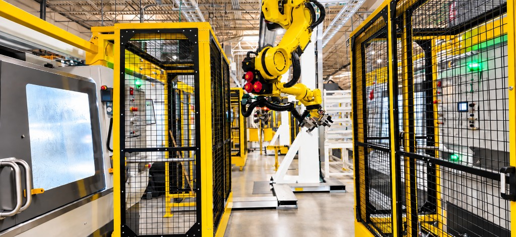Yellow FANUC robot in a guarded automation cell beside CNC equipment