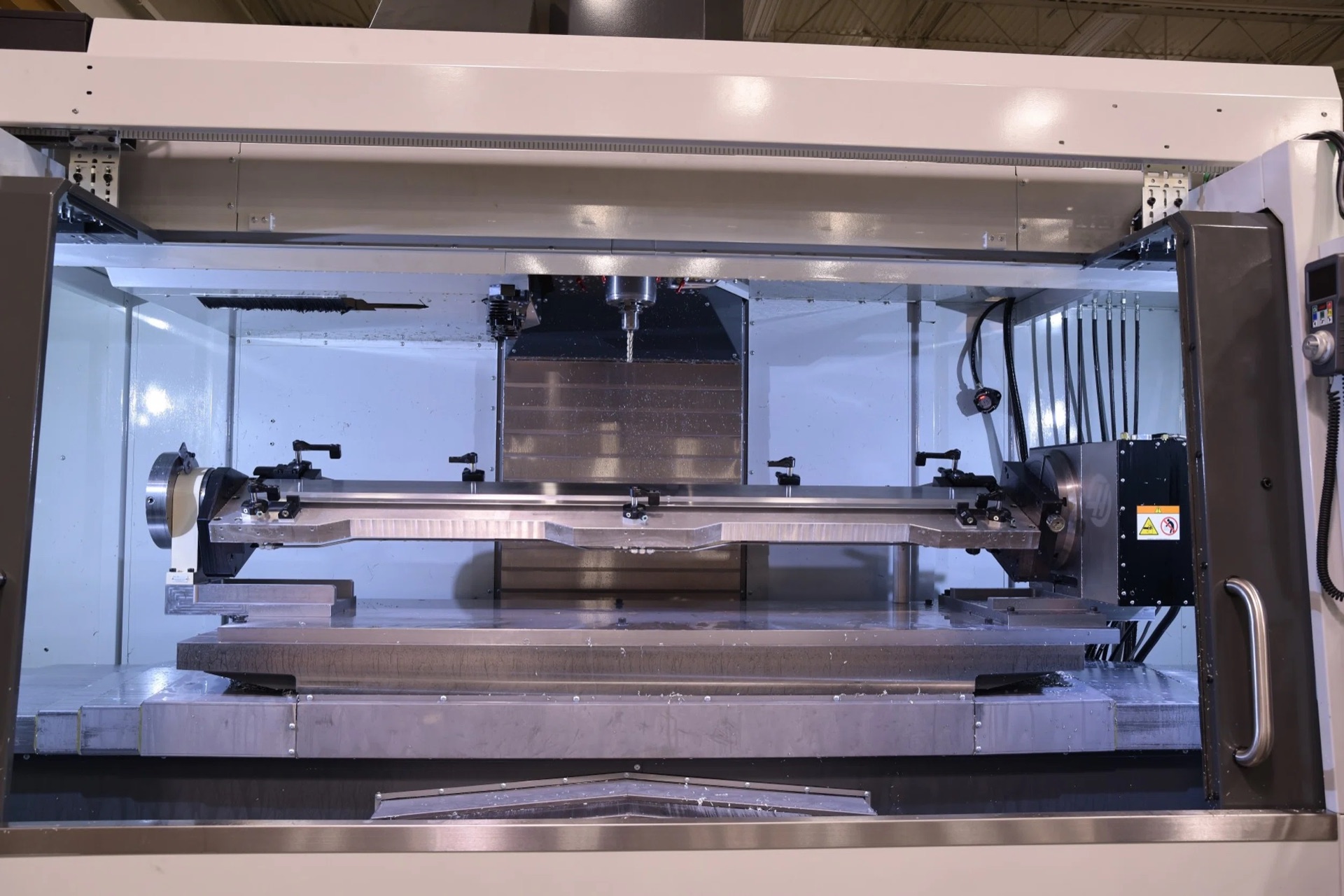 Interior of a 5-axis machining center with a custom trunnion fixture holding a large workpiece